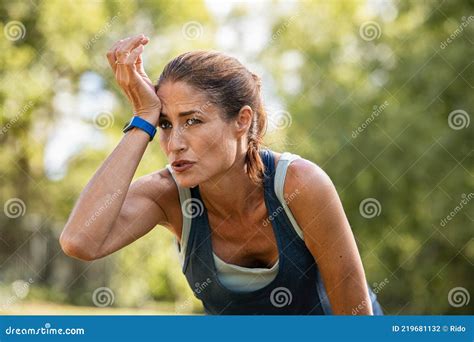 Tired Mature Runner Wiping Sweat After Workout At Park Stock Photo