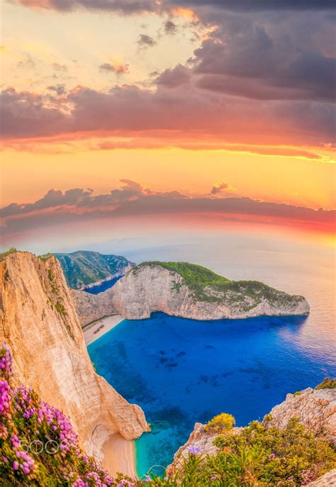 Navagiobeachwithshipwreckandflowersagainstsunsetonzakynthos