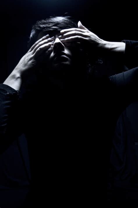 A Man Covering His Eyes In The Dark