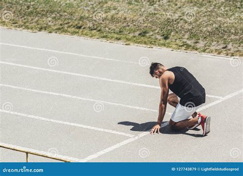 Side View Of Male Sprinter In Starting Position On Running Stock Image