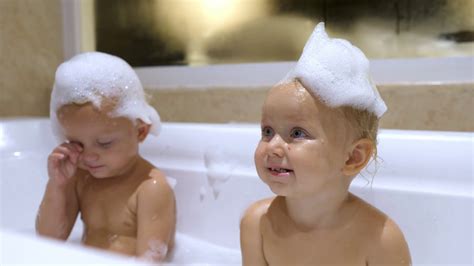 Adorable Tired White Twins Taking Bath With Soap Bubbles On Their Heads