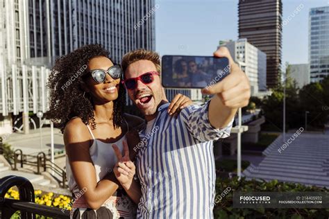 Cheerful Multiracial Couple Posing For Selfie While Standing On Background Of Modern City — Love