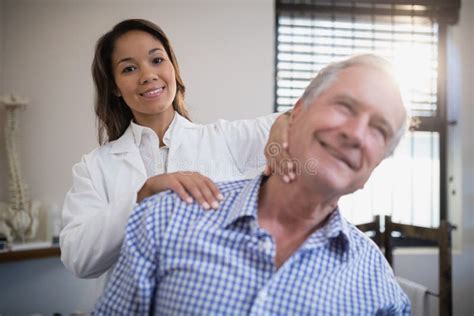 Portrait Of Smiling Female Therapist Giving Neck Massage To Senior Patient Stock Image Image