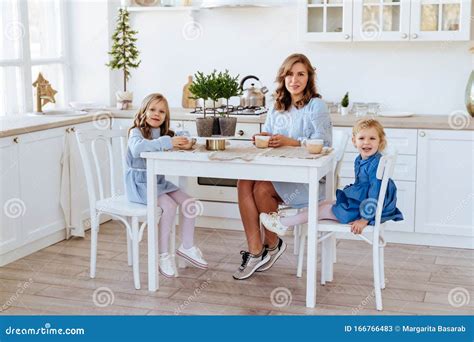 Mom With Her Two Children Sitting On The Kitchen Table Stock Image