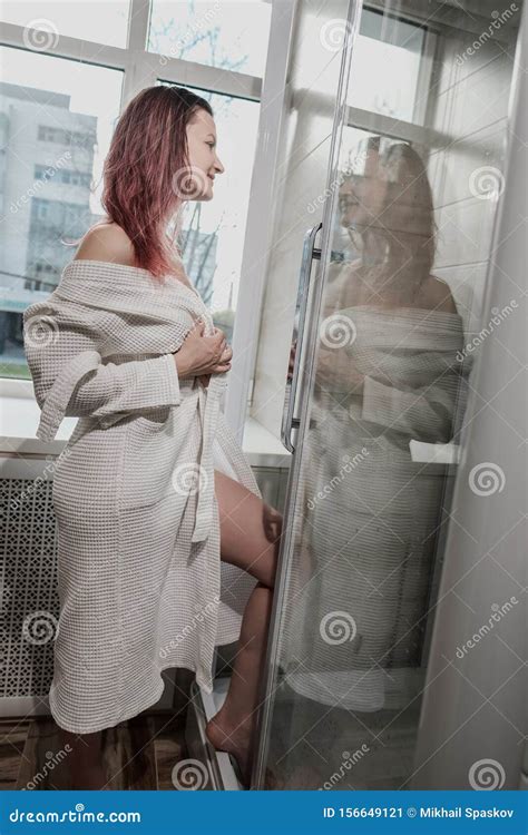 Young Beautiful Woman In White Coat And Towel In Bathroom Takes A Shower And Smiles Stock Image