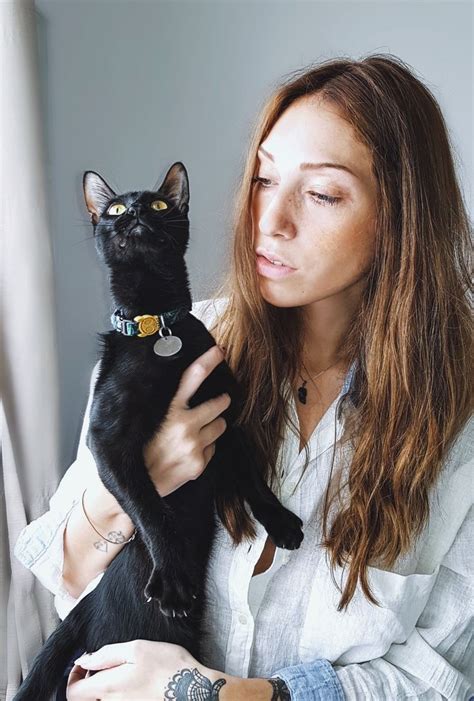 A Woman Is Holding A Black Cat In Her Lap And Looking At Its Face