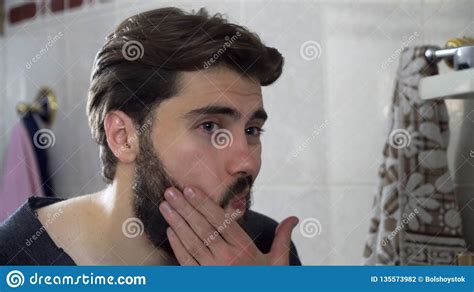 Retrato Do Homem Novo Do Adolescente Que Olha Si Mesmo Em Um Espelho Do Banheiro Da Casa Que Faz