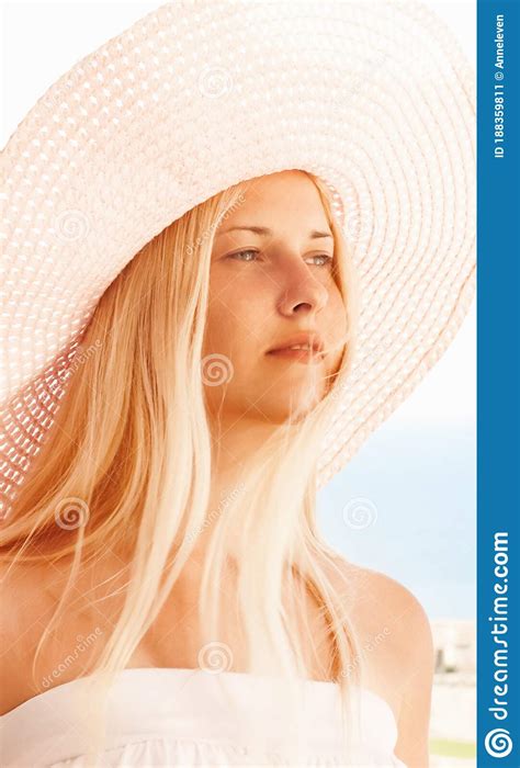 Woman With Blond Hair Wearing Hat Enjoying Seaside And Beach Lifestyle In Summertime Holiday