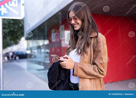 Pretty Young Woman Using Her Mobile Phone While Standing In The Street