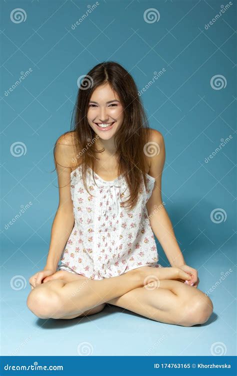 Beautiful Cheerful Teen Girl Sitting And Looking At Camera Over Blue