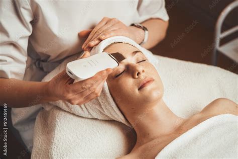 caucasian woman receiving facial procedure of cleansing the skin with ultrasound scrubber