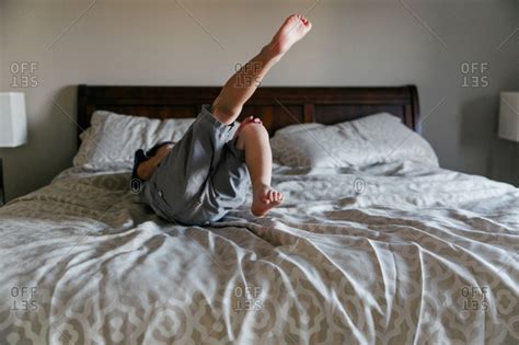 Boy Rolling Around On Bed Stock Photo OFFSET