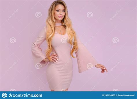 portrait of beautiful blonde girl with long hair and tanned body wearing pink dress stock image