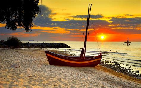 Little Sailboat On A Beach At Sunset
