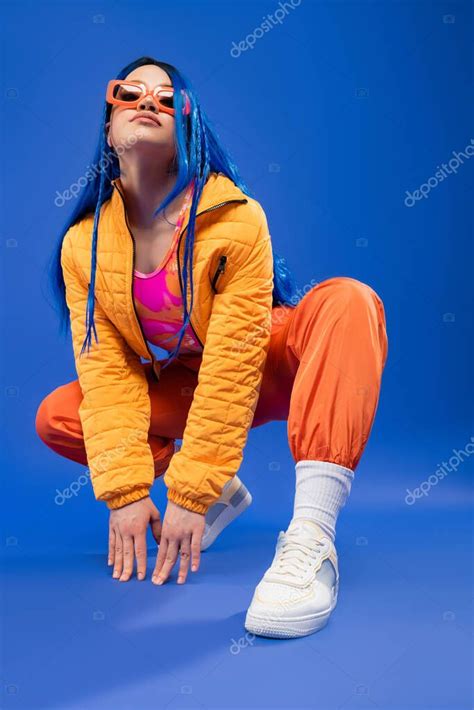 Longitud Completa De La Joven Modelo Femenina Con El Pelo Azul Y Gafas De Sol De Moda Sentado En