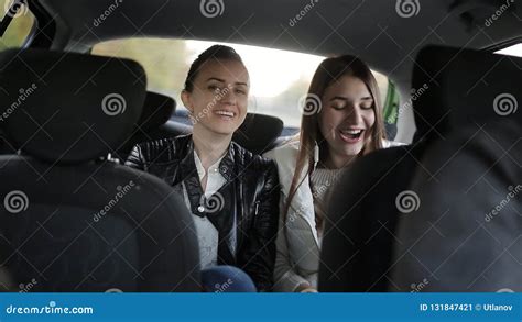 Two Girls Riding In A Taxi In The Back Seat Talking And Listening To