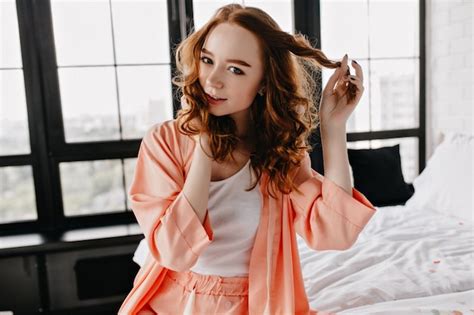 Free Photo Excited Young Woman In Pajama Playing With Her Curly Hair