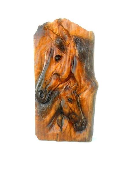 A Horse And Foal Carved Into A Piece Of Wood On A White Background