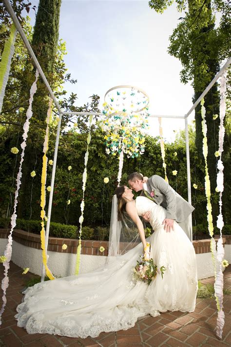 Lush florals and candles line. whimsical garden wedding outdoor venue bride groom kiss ...