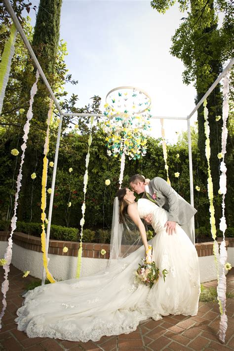 Lush florals and candles line. whimsical garden wedding outdoor venue bride groom kiss ...