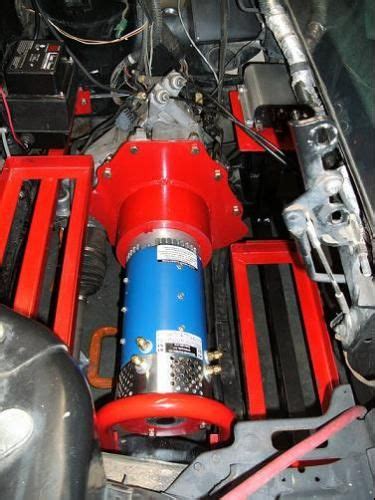 The Engine Compartment Of A Car With Red And Blue Parts On Its Hood