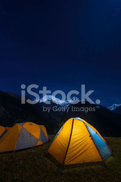 Starry Skies Above Snowy Mountains And Yellow Tent Base Camp Stock