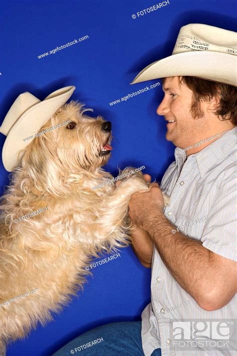 Fluffy Brown Dog And Male Caucasian Young Adult Wearing Cowboy Hats