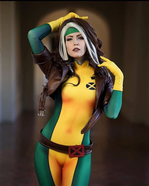 a woman in a yellow and green bodysuit posing for the camera with her hands on her head