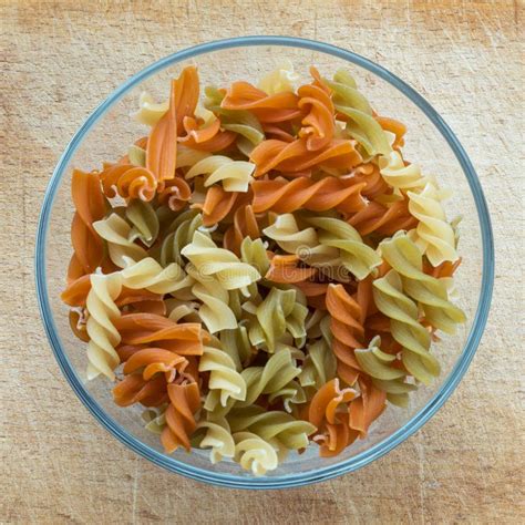 Multicolor Spiral Macaroni Pasta In A Glass Bowl On A Wooden Cutting