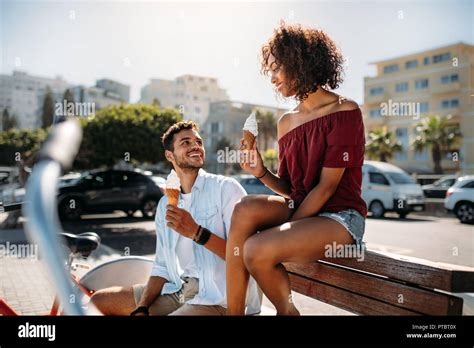 Romantic Couple Sitting On A Bench In Street Eating Cone Ice Cream