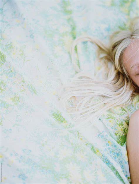 Blonde Girl Laying On Vintage Floral Sheets With Bits Of Hair On Film