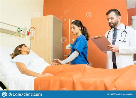 Doctor And Nurse Examining Female Patient At Hospital Stock Photo