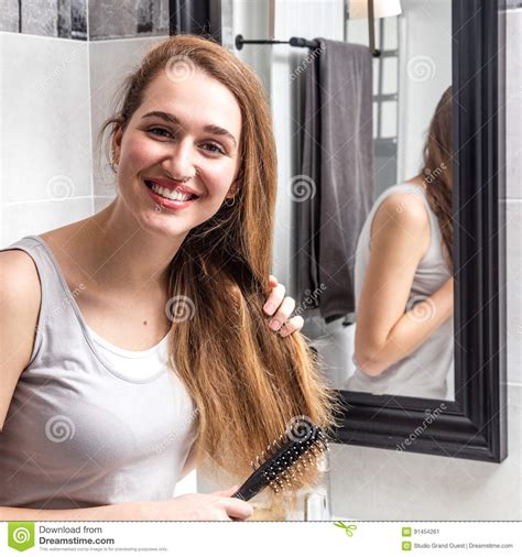 Joyous Beautiful Young Woman Standing Brushing Her Long Dry Hair Stock
