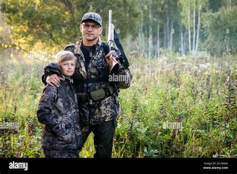 Father And Son Walking Together Outdoors With Rifle For Hunting Stock