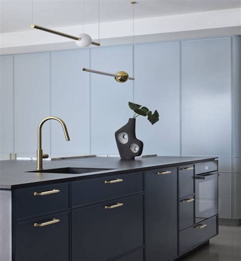 A Modern Kitchen With Blue Cabinets And Gold Handles On The Countertop