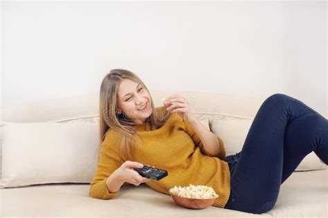 Cute Smilling Young Woman Watching Tv And Relaxing On Sofa At Ho Stock