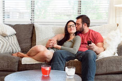 Caucasian Man Kissing Cheek Of Woman On Sofa Stock Photo Dissolve