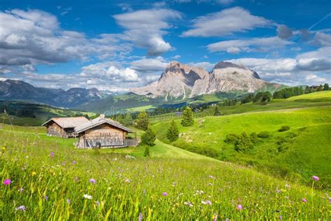 Alpine Scenery In The Dolomites With Green Meadows And Mountain Chalets