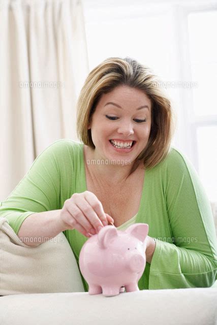 Woman Depositing Money Into Piggy Bank 20025203554 の写真素材・イラスト素材｜アマナイメージズ