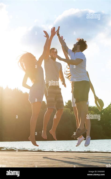 Four Friends High Fiving At A Lake In Backlight Stock Photo Alamy