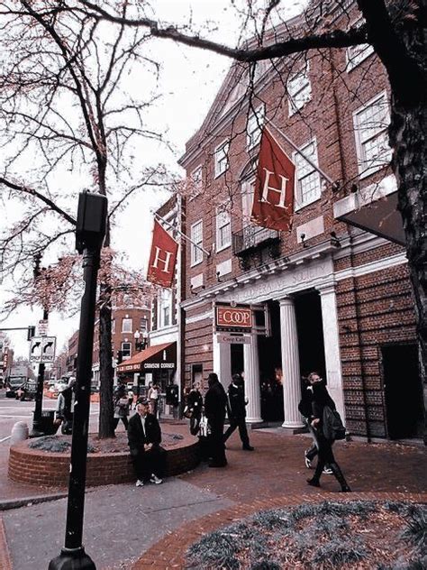 People Walking On The Sidewalk In Front Of A Building With Red Flags