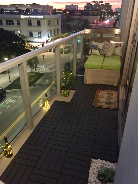 A Balcony With Green Couches And Rugs On The Floor Next To A City Street