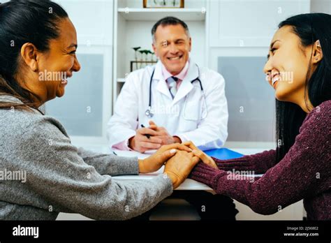 Smiling Doctor And Happy Adult Female Patients In Doctors Office