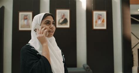 سيدة عربية خليجية سعودية تقوم بجر حقيبة السفر، التحدث من خلال الهاتف المحمول، جلسة تصوير داخل