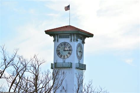 A White Clock Tower With A Flag On Top