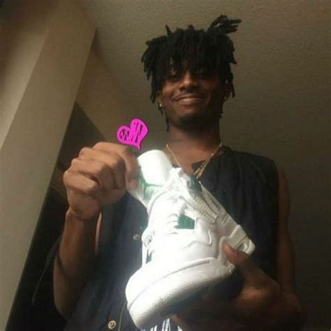 A Man Holding Up A White Sneaker With A Pink Sticker On It