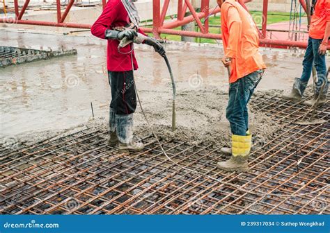 Construction Workers Stir The Cement With A Hose On The Floor Of The