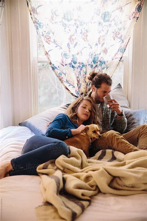 Couple Relaxing On Bed With Their Dog By Stocksy Contributor