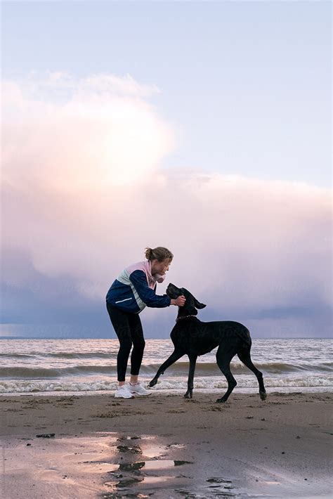 Woman Playing With Dog Pet On Morning Beach By Stocksy Contributor