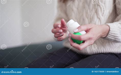 A Woman Opens A Jar Of Medicine Pours A Pill Into Her Palm And Takes